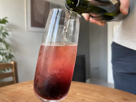 Cidre brut versé doucement dans un verre avec la crème de cassis